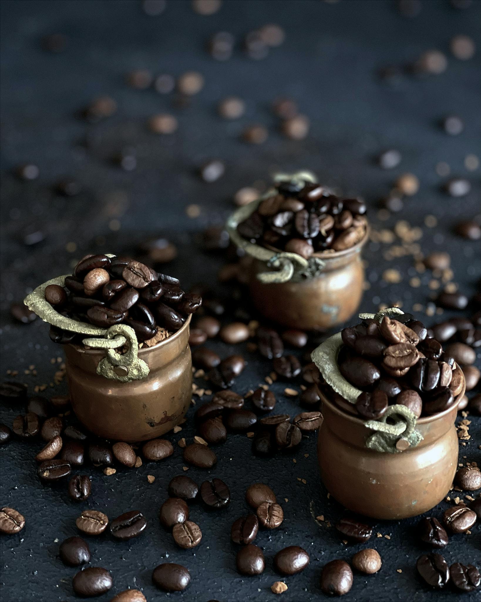 Aesthetic arrangement of coffee beans in decorative copper pots, evoking Turkish coffee culture.